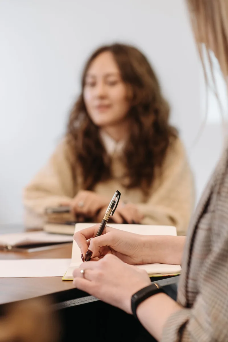 A participant takes handwritten notes during a meeting.