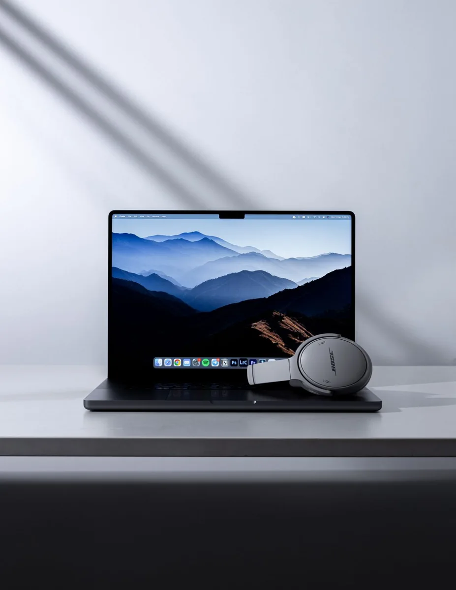 Headphones rest beside an open laptop on a desk.