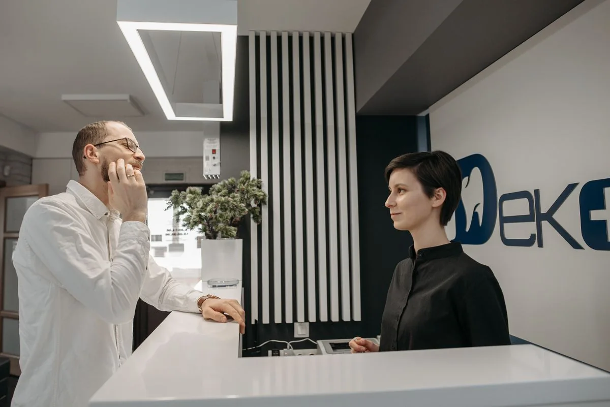 A patient speaks with a receptionist at a dental practice.